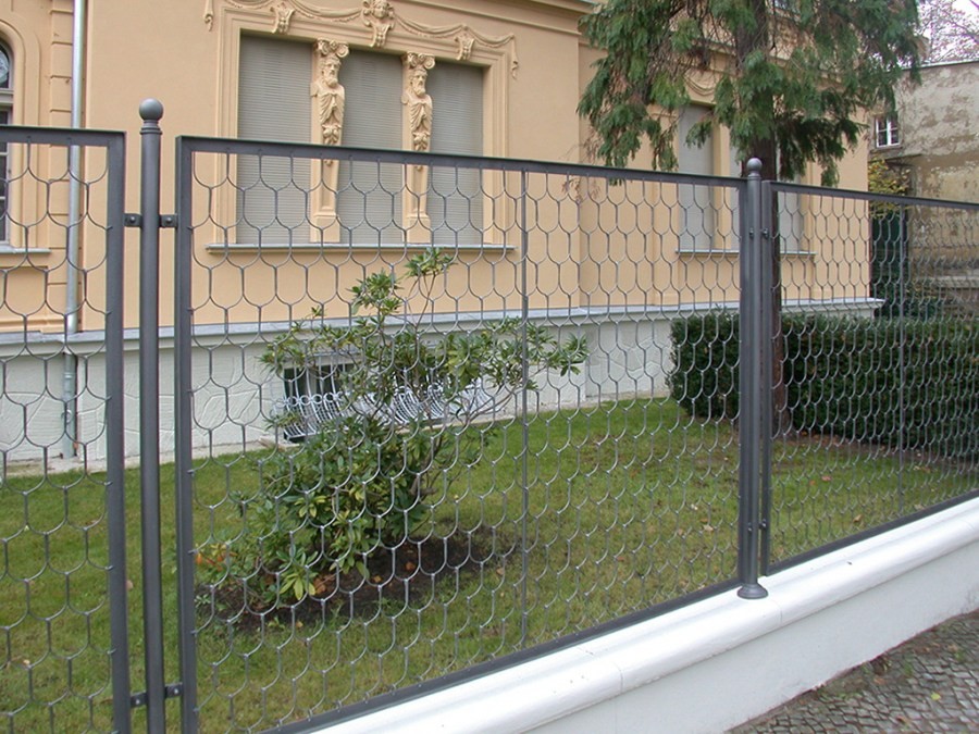 Сетчатый забор в палисаднике перед кирпичным домом