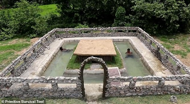 As a finishing touch, they create a wall around the pool, and a stone archway as an entrance. After all their hard work, the two men take a well-deserved dip in their new pool 